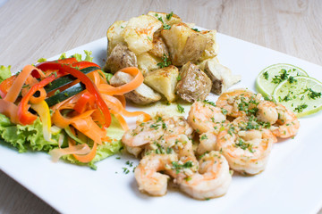 Garlic shrimp, bathed in garlic sauce, accompanied by potatoes and vegetables