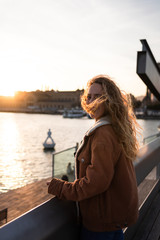 Blond girl with curly hair looking at the sunset by the sea in Barcelona, Catalonia, Spain.