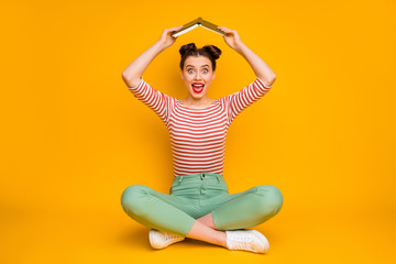 Full length photo of pretty lady sit floor hold book above head avoid do homework open mouth...