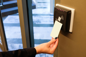 Women hand reaching to use RFID key card to access to office building area and workspace. In...