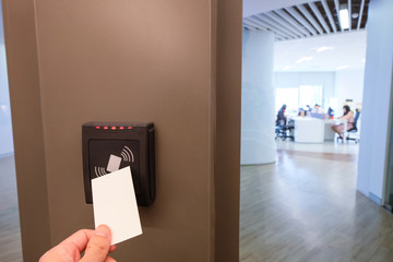 Men hand reaching to use RFID key card to access to office building area and workspace. In building...