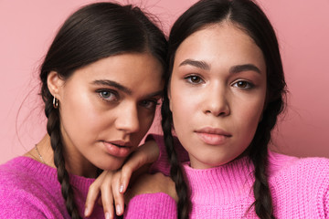 Image of two attractive teenage girls with braids looking at camera