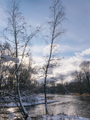 winter landscape with wild fast flowing river, snow covered land