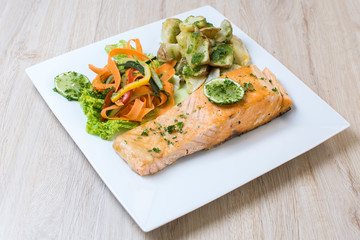 Salmon with garlic and lemon, accompanied by sauteed vegetables and spicy potatoes