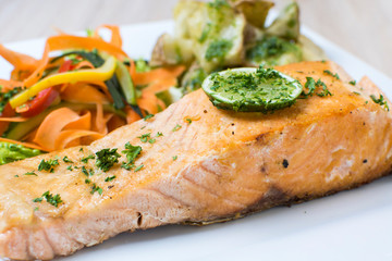 Salmon with garlic and lemon, accompanied by sauteed vegetables and spicy potatoes