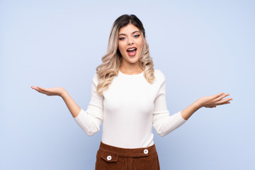Young teenager girl over isolated blue background with shocked facial expression