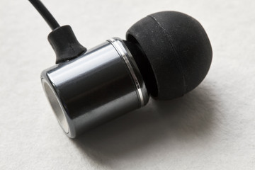 One earphone lies on white background. Closeup