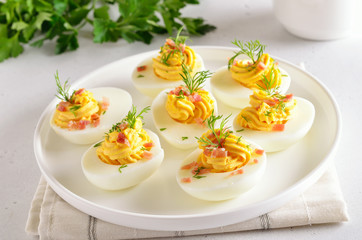 Deviled stuffed eggs with egg yolk, bacon, mustard and dill