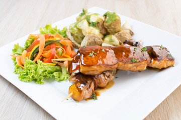 Pork skewer, accompanied by spicy potatoes and vegetables