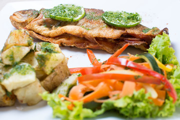 Baked trout, stuffed with ham and cheese, accompanied by spicy potatoes and vegetables