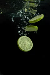  Kalk valt in het water. Verse citrusvruchten in het water. Splash van water vallen in het schijfjes limoen. © MadCat13Shoombrat
