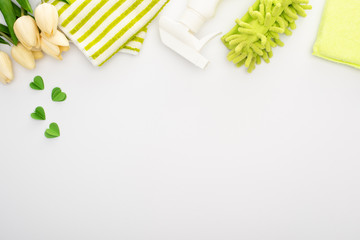 top view of spring tulips and green cleaning supplies on white background