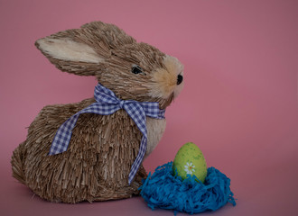 Easter bunny with purple bow and green egg  on pink background.