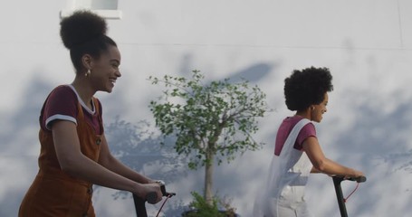 Two mixed race women riding electric scooter - Powered by Adobe