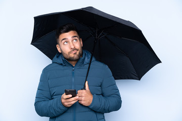 Man holding an umbrella over isolated background © luismolinero