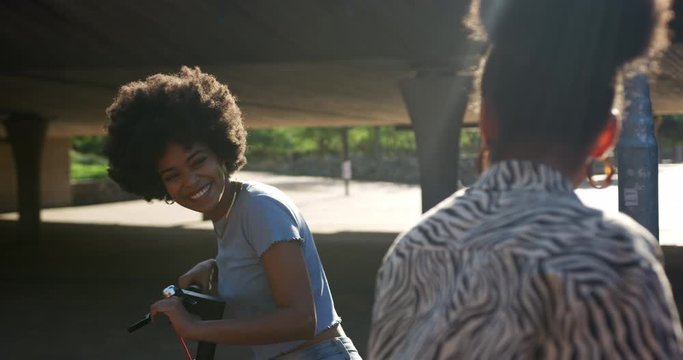 Two mixed race women laughing under bridge