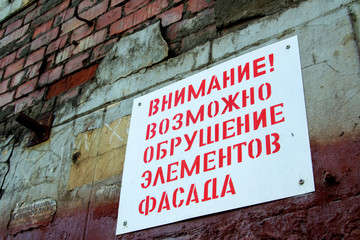 plate on an old brick wall, restoration of an old building. Russian text carefully collapse of the facade