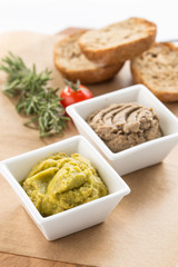 homemade guacamole and mushroom paste in bowl and sliced bread on wooden board isolated on white background