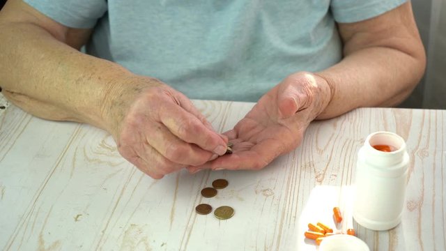 Old lady counting euro coins in hands, pillbox with orange pills, lack of money to buy a pills concept