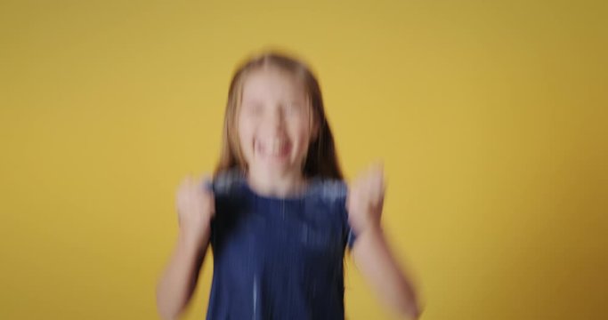 Portrait of happy caucasian little girl smiling, looking at camera. Redhead female child jumping for happiness with cheerful emotions and feelings of joy. Copy space, slow motion