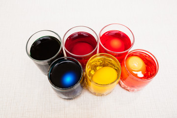 Painting process of Easter eggs by dye in the glasses. Home decorations for the holiday.
