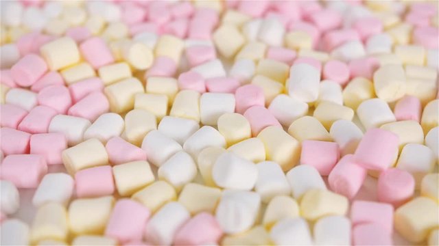 colorful and tasty marshmallows rotating on white background cloes up