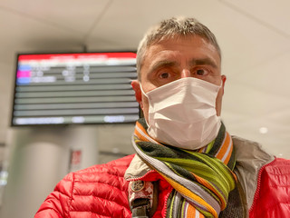 Coronavirus Covid-19 is spreading across Italy and Europe. Man at the airport wearing protective...
