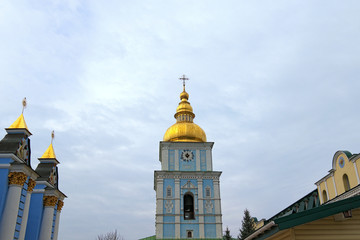 Wide-angle landscape view of bell-tower of famous Saint Michael's Golden-Domed Monastery ("Mykhailiv'skyj Sobor") in Kyiv. Cloudy blue sky in the background