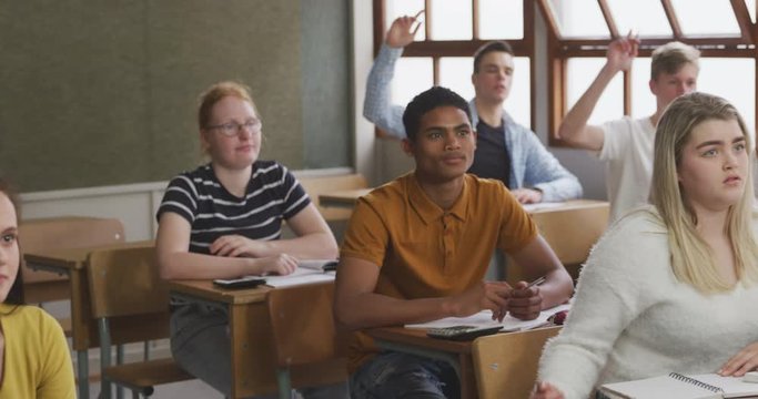 Student raising his hand in high school class