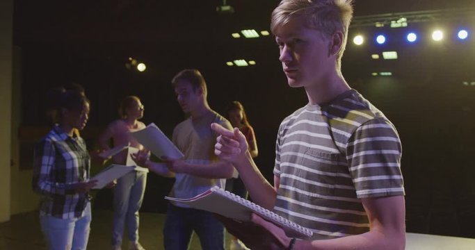 Students preparing before a high school performance in an empty school theater 