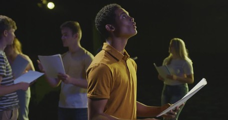 Students preparing before a high school performance in an empty school theater 