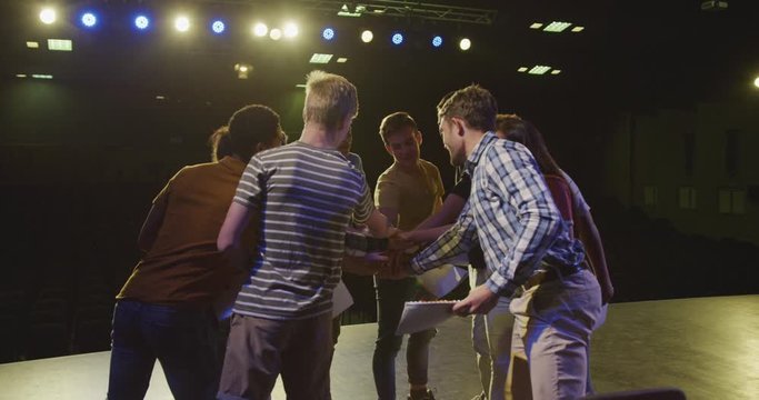 Students preparing before a high school performance with their teacher in an empty school theater 