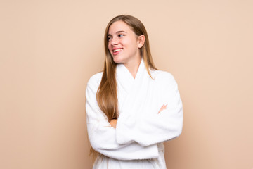 Teenager girl in a bathrobe over isolated background laughing