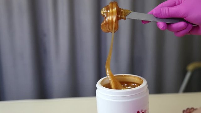Liquid sugar for skin epilation. Close up shot. depilation and beauty concept - sugar paste or wax honey for hair removing with wooden waxing spatula sticks