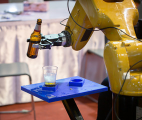 Futuristic robotic arm pouring beer into a glass