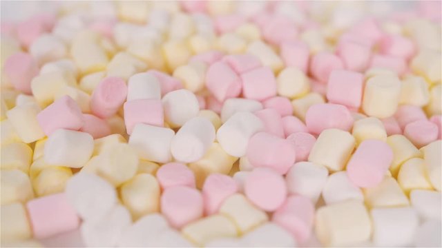 colorful and tasty marshmallows rotating on white background cloes up
