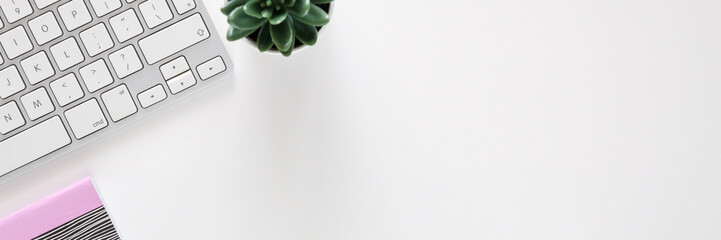 A desk in a home office. View from above. White empty copy space. Imac computer, notebook and succulent. Panoramic photo