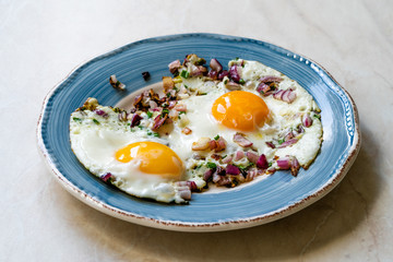 Sunny Side Up Fried Eggs with Red Onions and Chives for Breakfast in Plate.