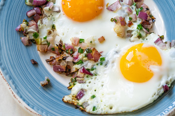 Sunny Side Up Fried Eggs with Red Onions and Chives for Breakfast in Plate.