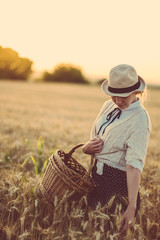 Retro / vintage woman at summer fields in sunset