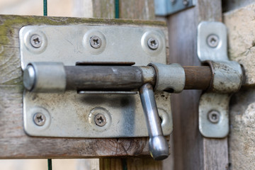 Focus on steel bolt of sliding lock on garden fence