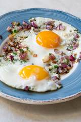 Sunny Side Up Fried Eggs with Red Onions and Chives for Breakfast in Plate.