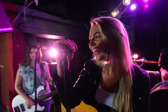 Caucasian woman singing with her band behind