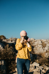 Woman with hijab standing above old city of Dubrovnik and taking photos with her camera. She is happy and relaxed. She is enjoying sunset. 