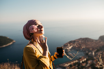 Woman with hijab standing above old city of Dubrovnik. She is happy and relaxed. She is enjoying sunset. 