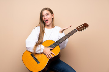 Teenager girl with guitar over isolated background with shocked facial expression