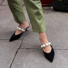 girl in a light green trouser suit in transparent tights with large pearls and pointed black...