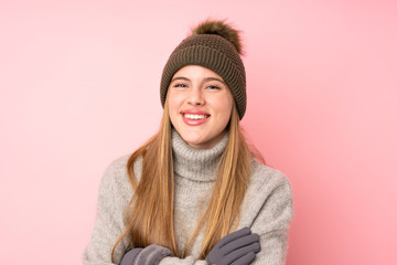 Young teenager girl with winter hat over isolated pink background laughing