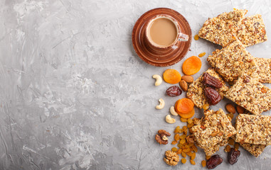 Homemade granola from oat flakes, dates, dried apricots, raisins, nuts with a cup of coffee on a gray concrete background. Top view.