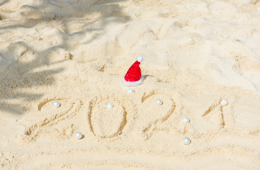 Happy New Year 2021 text  in the sand with Christmas ball, travel and vacation concept